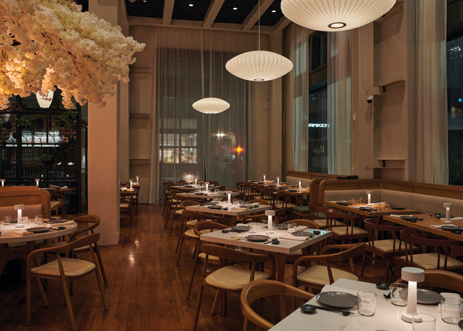 Above custom furnishings, including wishbone-style chairs, lantern pendants give the dining room a warm glow. Image courtesy of Joey Wrinn