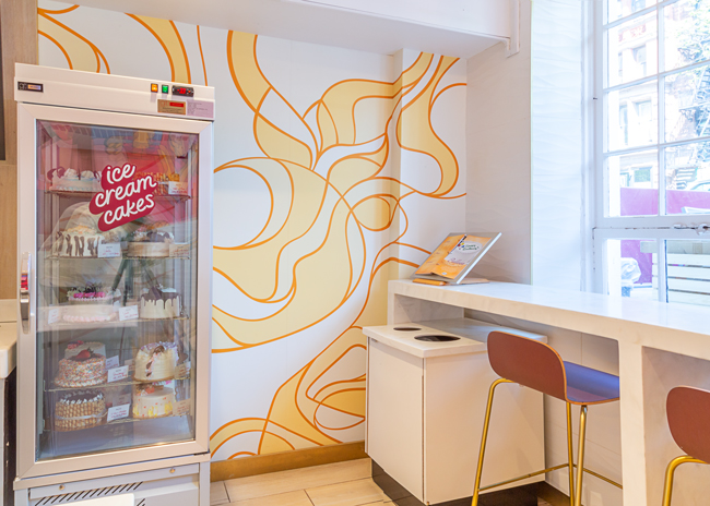  The tapestry wall, with its swirling yellow and golds, evokes flavors mixed in with ice creams. It is a signature element in the new Häagen-Dazs design.