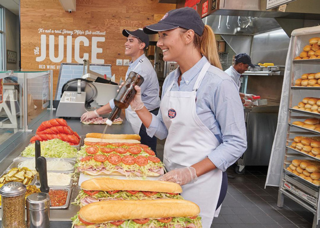 Jersey Mikes continually monitors operations at stores including how makeline staff apply oil and vinegar “juice” to subs to ensure consistency. Image courtesy of Jersey Mike’s.