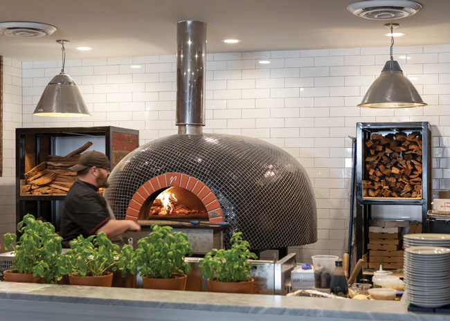 Some restaurants like to showcase a piece of equipment, like a pizza oven, with a glimpse of the kitchen, says Brian Thomas of DP3. Image courtesy of Kris Decker, Firewater Photography