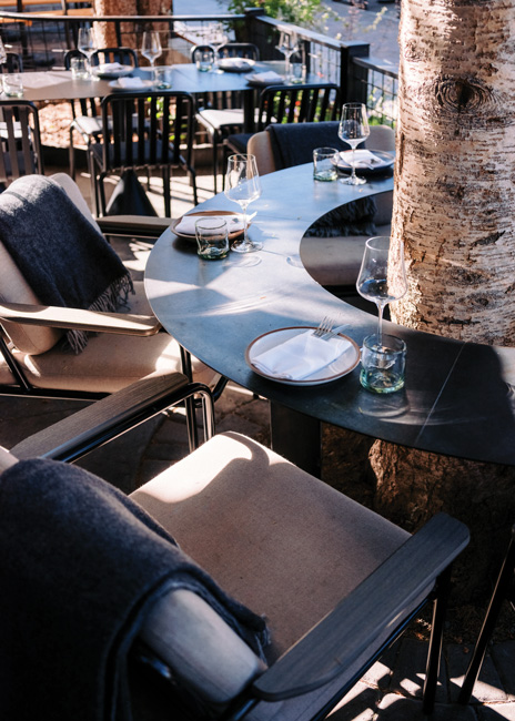 Custom black steel tables were built around existing trees on the sidewall patio area, providing a unique and practical seating option.