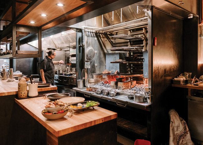 : An open kitchen with live-fire cooking is a cornerstone of Two Twelve’s concept. Seating plans and booth heights were strategically designed to maximize views to the action on the main level.